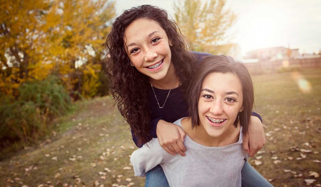 Two teens smiling with braces