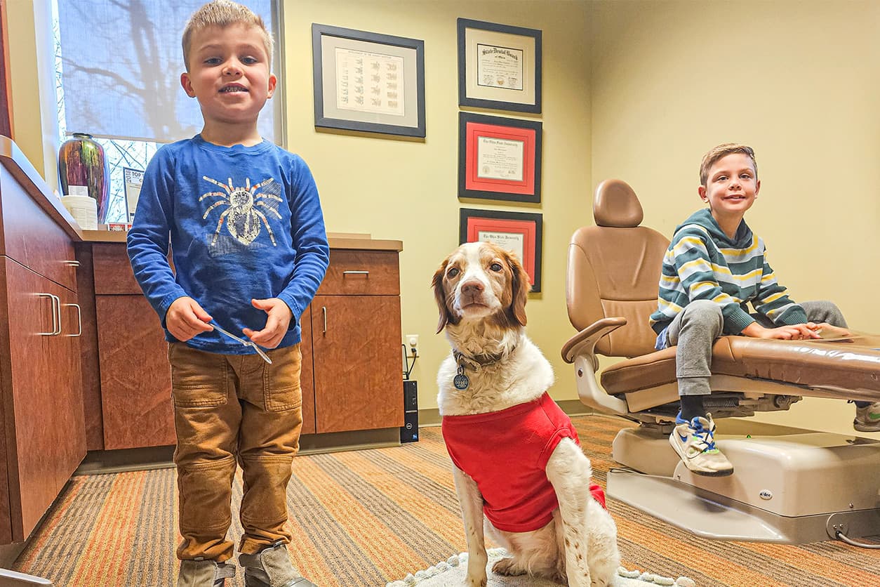 two kids with a dog at the practice as parents are understanding dental insurance